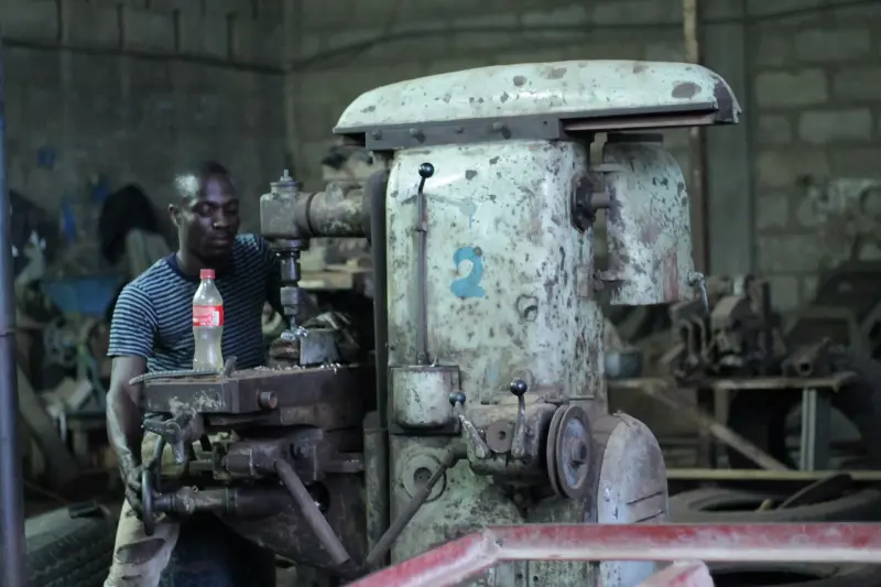 Ghanaian engineer operating machinery in a workshop